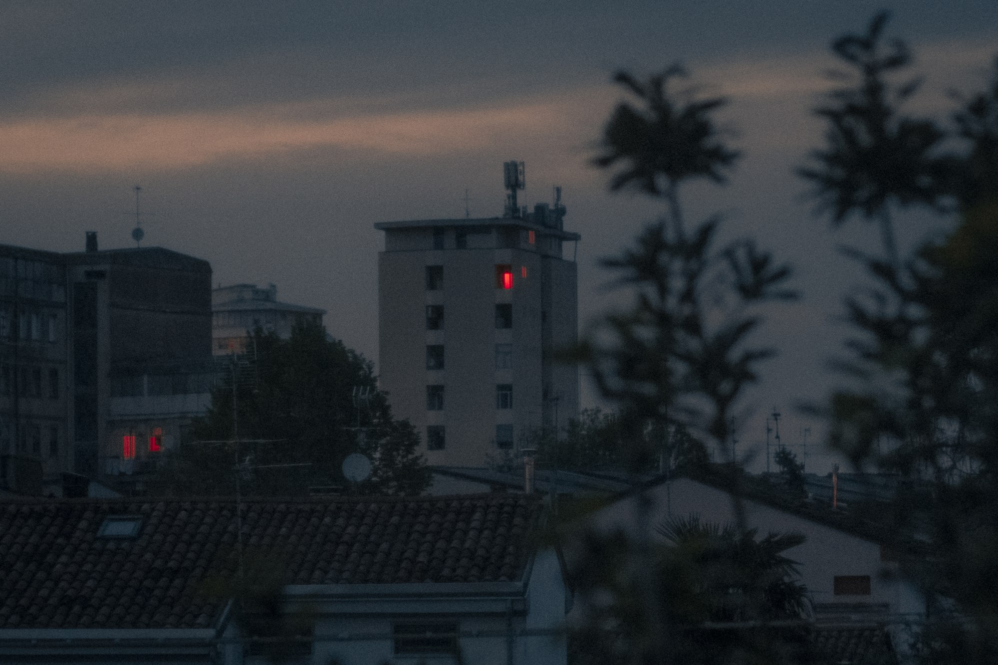 Un palazzo al crepuscolo con una finestra illuminata di rosso